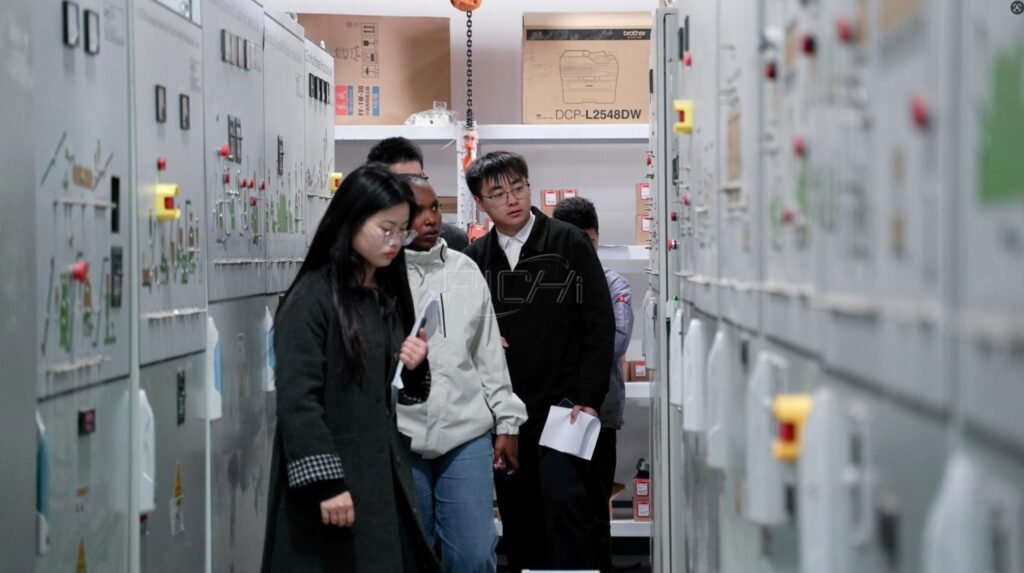Visitors reviewing pellet plant electrical control cabinets with manufacturing staff